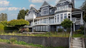 A large, multi-story house with a balcony, a staircase, and a view of a river. - 1BR 2BA Lower Unit with Lake Access - Prime Spot (Issaquah)