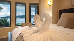 A hotel room with a bed, a chair, and large windows offering a view of a body of water and greenery. - 1BR 2BA Lower Unit with Lake Access - Prime Spot (Issaquah)