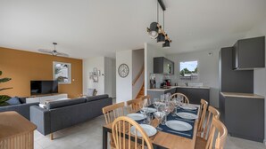 Un apartamento moderno con comedor, cocina, sala de estar y una escalera.