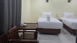 A hotel room with two beds, a wooden bench, a table, and a wall-mounted air conditioner. - Haad Somboon House (Bang Saphan)