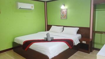 Ein Hotelzimmer mit Bett, Klimaanlage, Nachttisch und Wandleuchte.