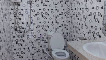 Un baño con inodoro, lavamanos y ducha con panel de control azul.