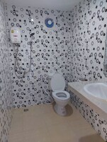 Un baño con inodoro, lavamanos y ducha con panel de control azul.