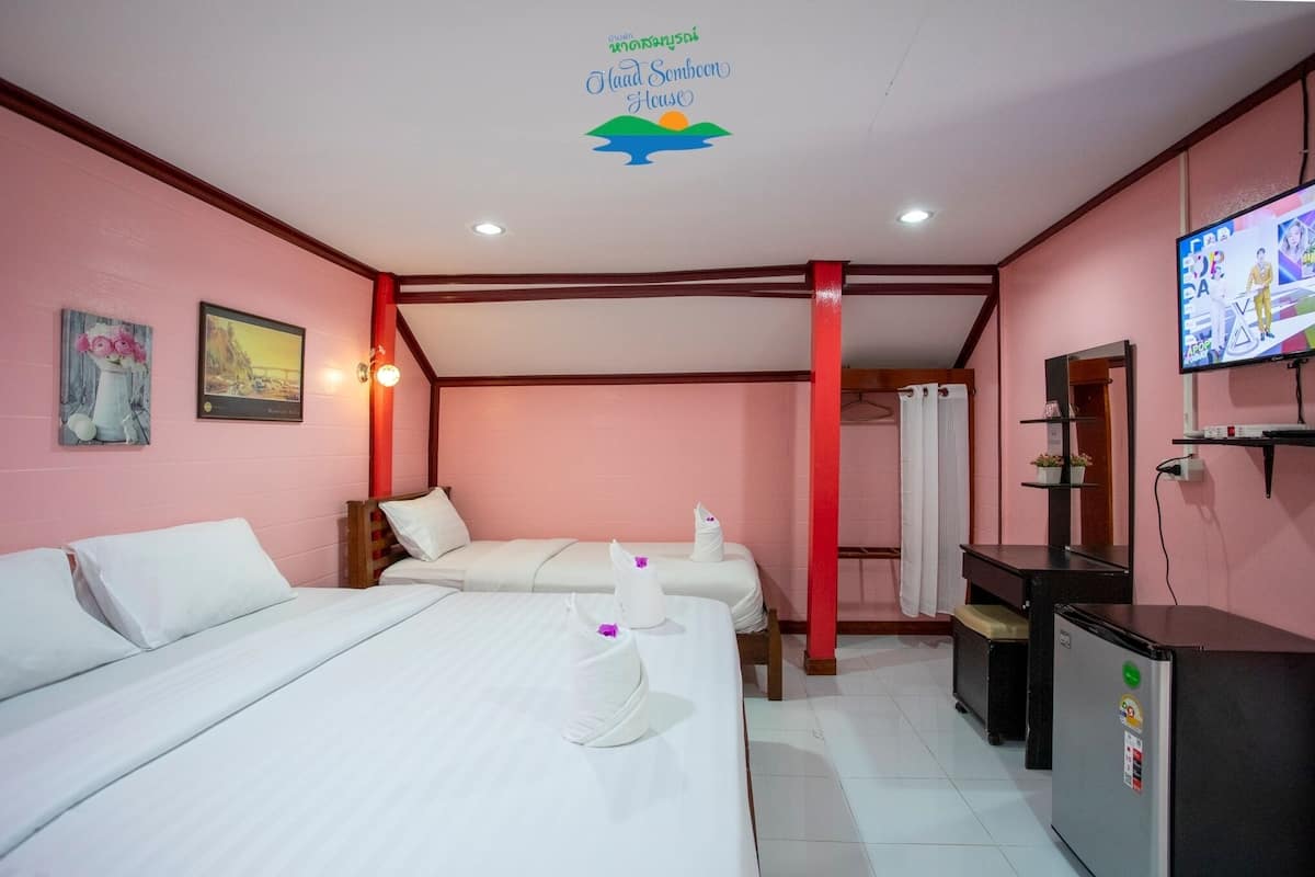 Habitación de hotel con dos camas, televisión, kitchenette pequeña y baño con cortina de ducha.