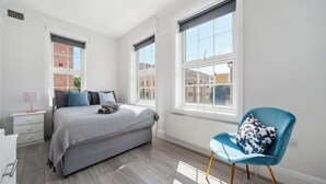 A bedroom with a bed, a chair, a nightstand, and a window. - King's Cross Boutique Apartment! ZONE 1 !!! (London)