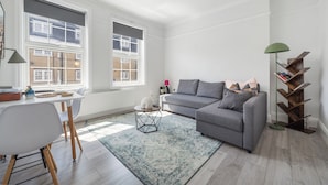 A modern living room with a grey sofa, a round coffee table, and a bookshelf. - King's Cross Boutique Apartment! ZONE 1 !!! (London)