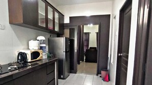 A compact kitchen with dark cabinets, a microwave, a refrigerator, and a coffee maker. - KLIA AIRPORT HOMESTAY 9 (Sepang)
