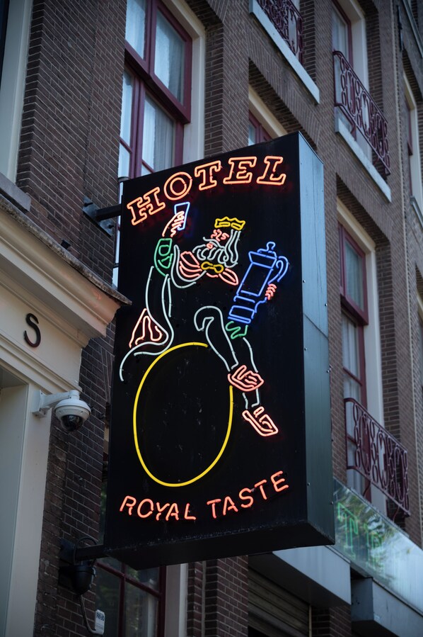 Ein Neon-Schild für ein Hotel namens "Royal Taste" mit einer Darstellung einer Person, die ein Bierglas hält.