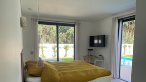 Une chambre moderne avec un lit, un bureau, une chaise, une télévision et une vue sur une piscine.