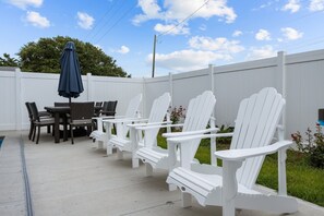 Relax in style with Adirondack chairs and a dining table, shaded by a stylish umbrella.