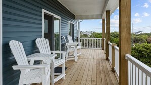 A wooden deck with white Adirondack chairs and a white railing. - Never Lost in Emerald Isle, NC (Emerald Isle)