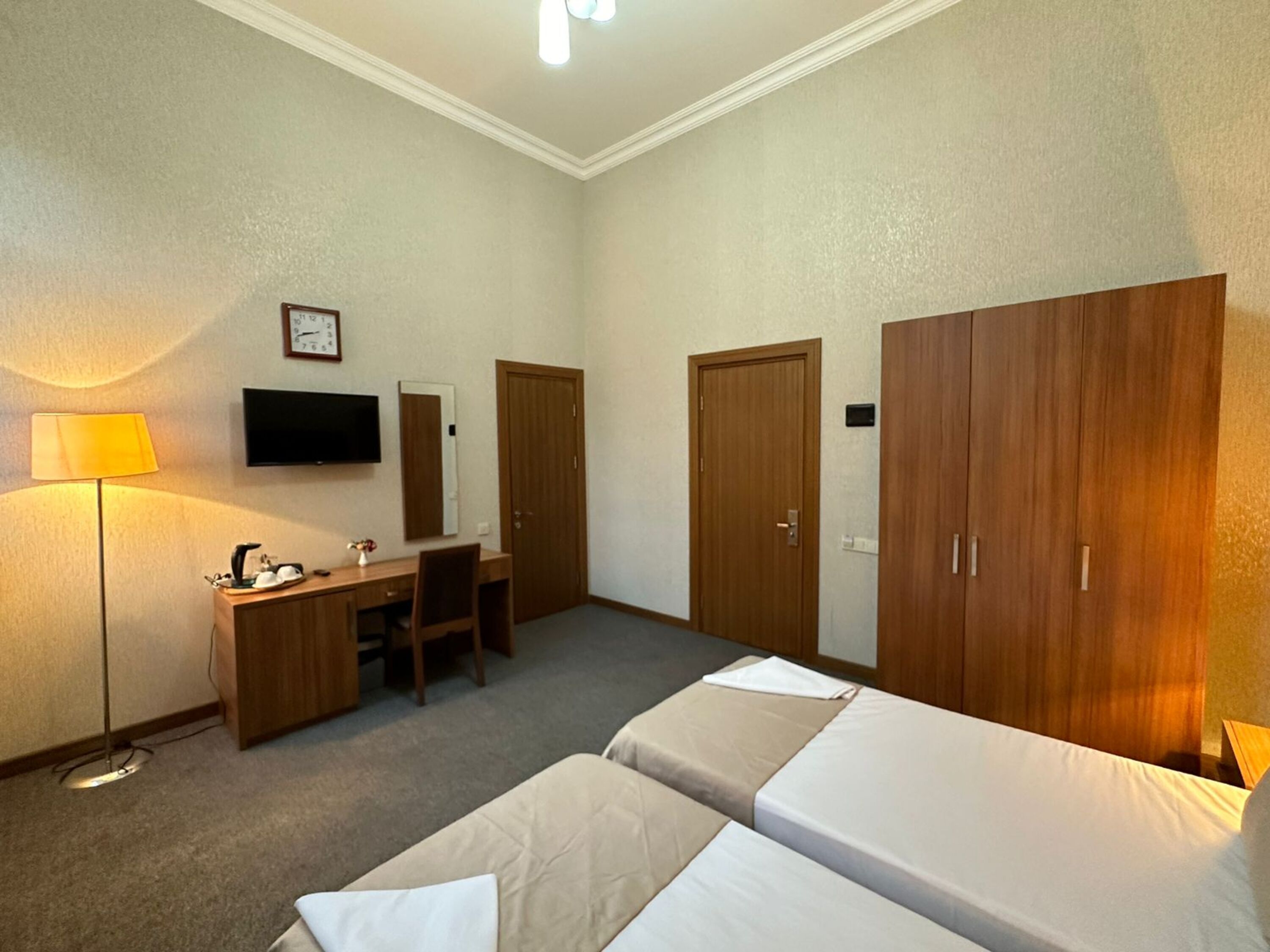 Une chambre d’hôtel avec deux lits, un bureau, une chaise, une télévision et une armoire.