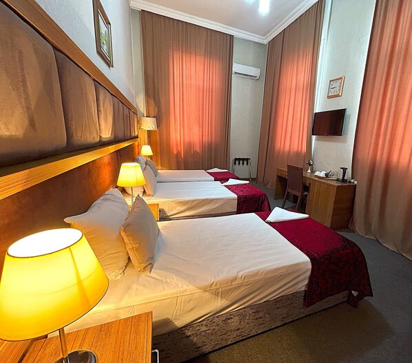 Une chambre d’hôtel avec deux lits, un bureau, une chaise, une télévision et un appareil de climatisation.