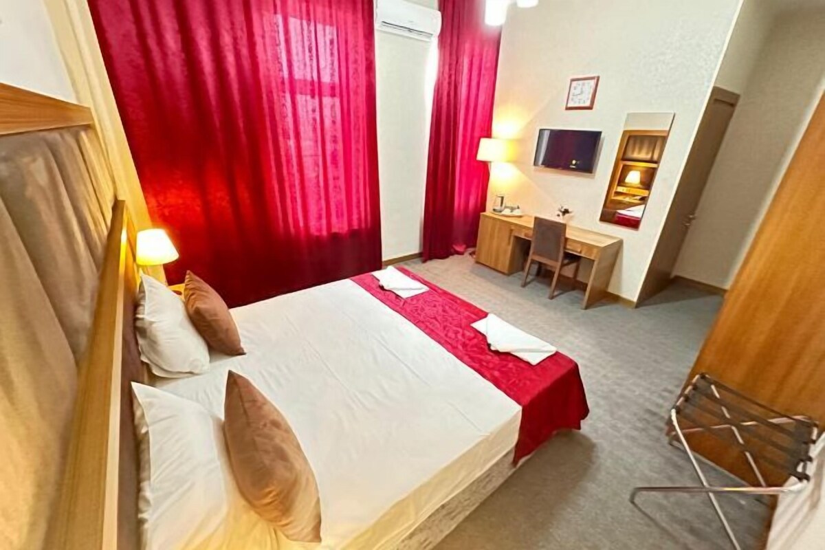 A hotel room with a bed, desk, chair, and a TV.