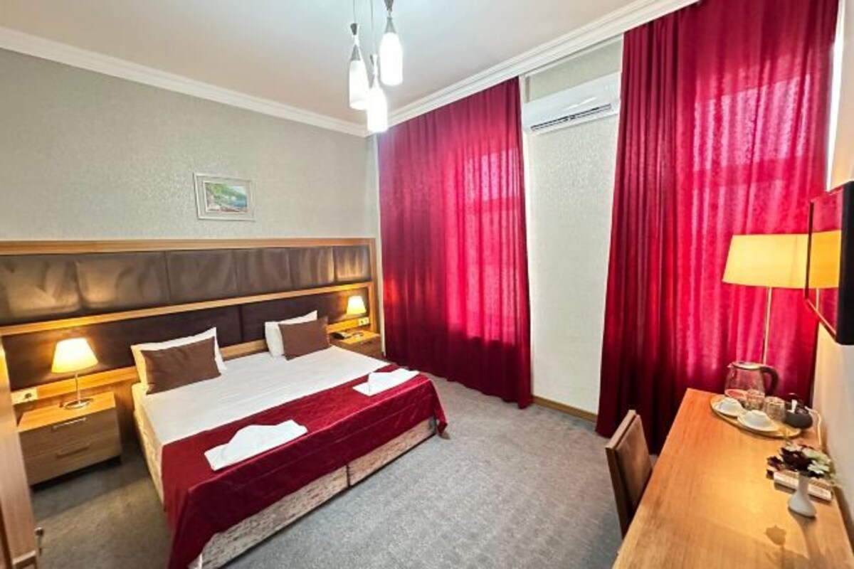 A hotel room with a bed, bedside tables, a desk, and a chair.