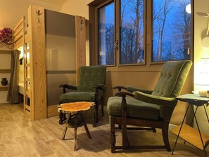 Relax in a serene space with a large window offering views of the outdoors, a comfortable seating area, and a unique wooden table.