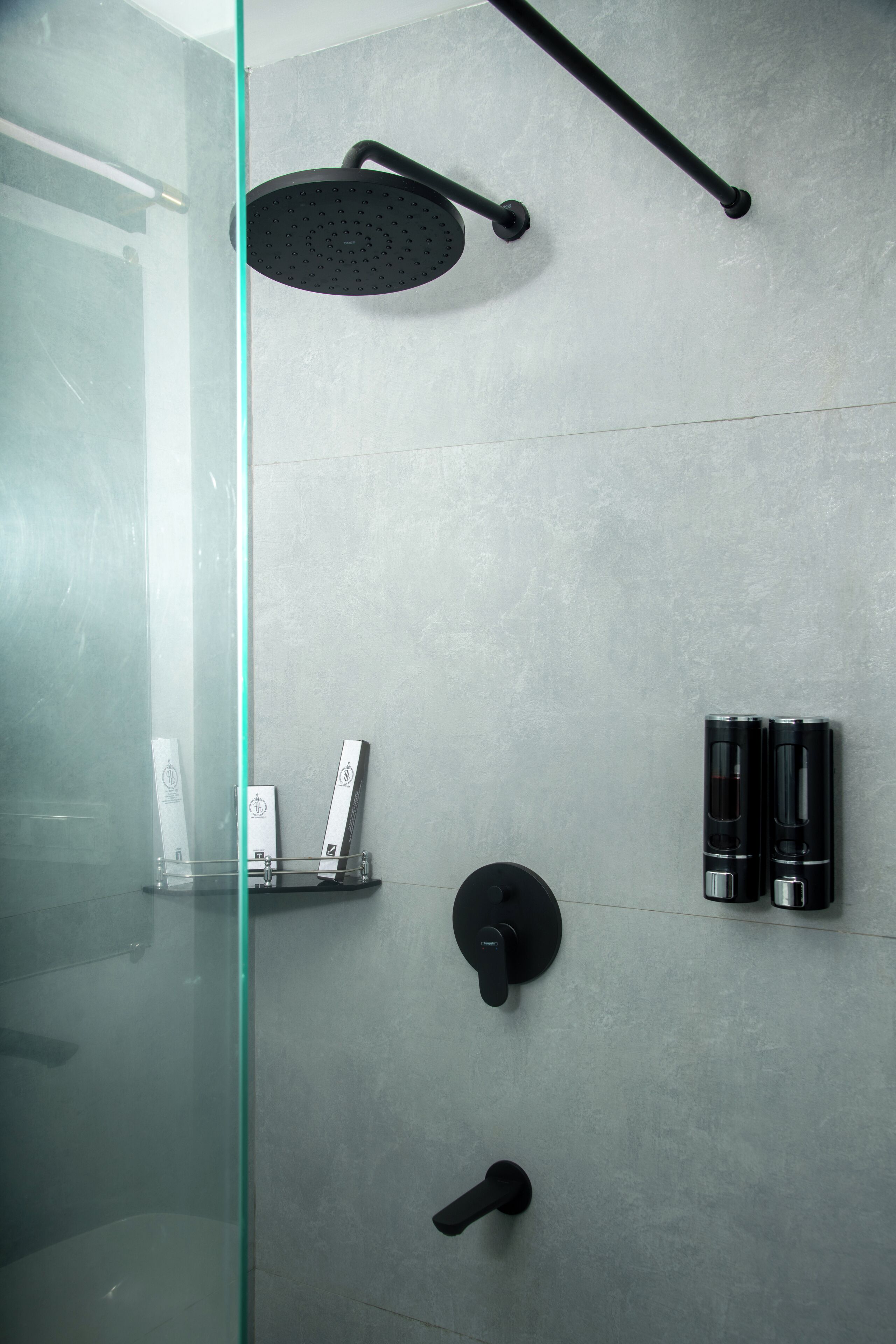 A modern shower with a glass enclosure, a handheld showerhead, and a wall-mounted control panel.