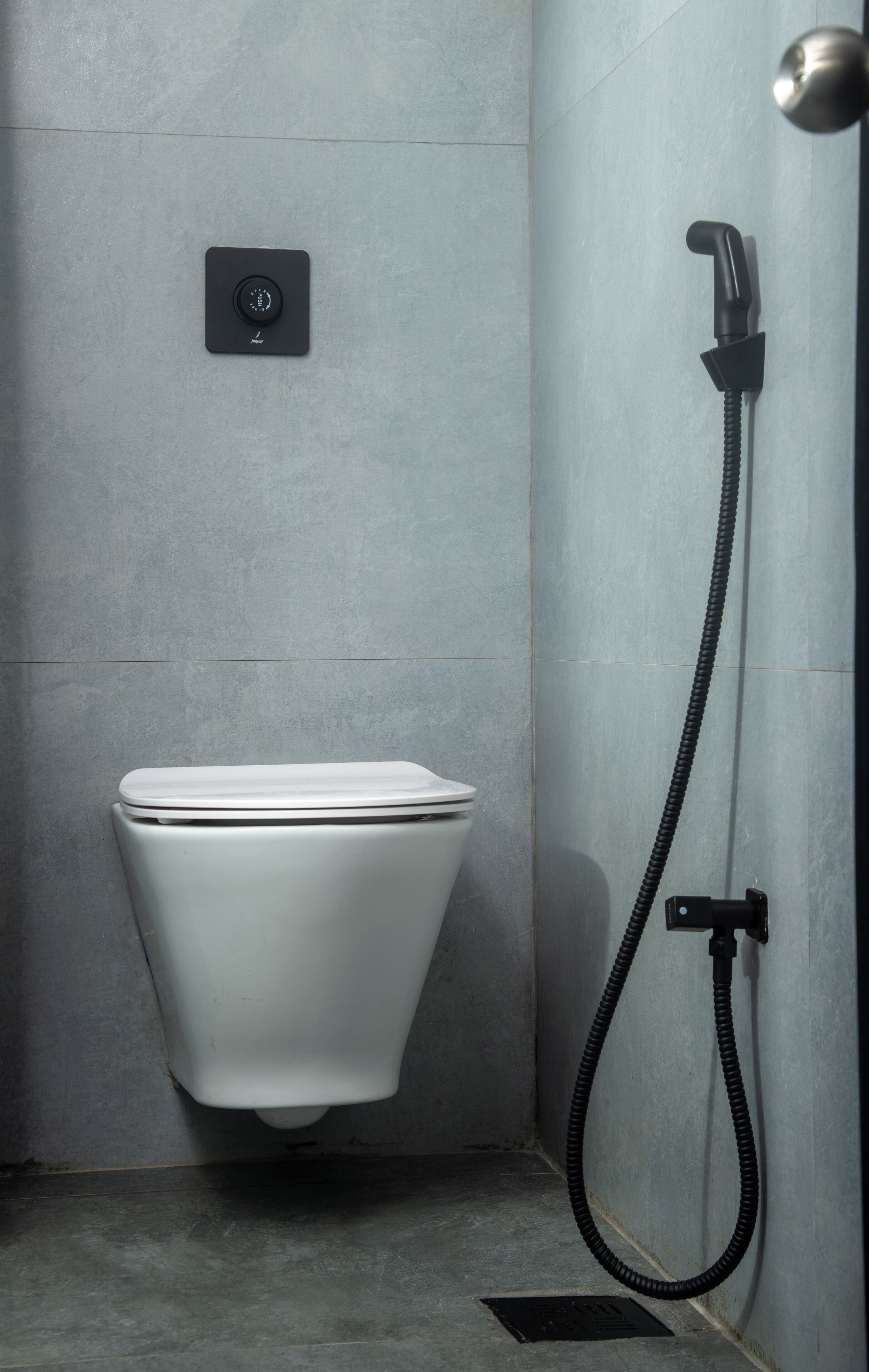 A modern bathroom with a toilet, a control panel, and a handheld showerhead.