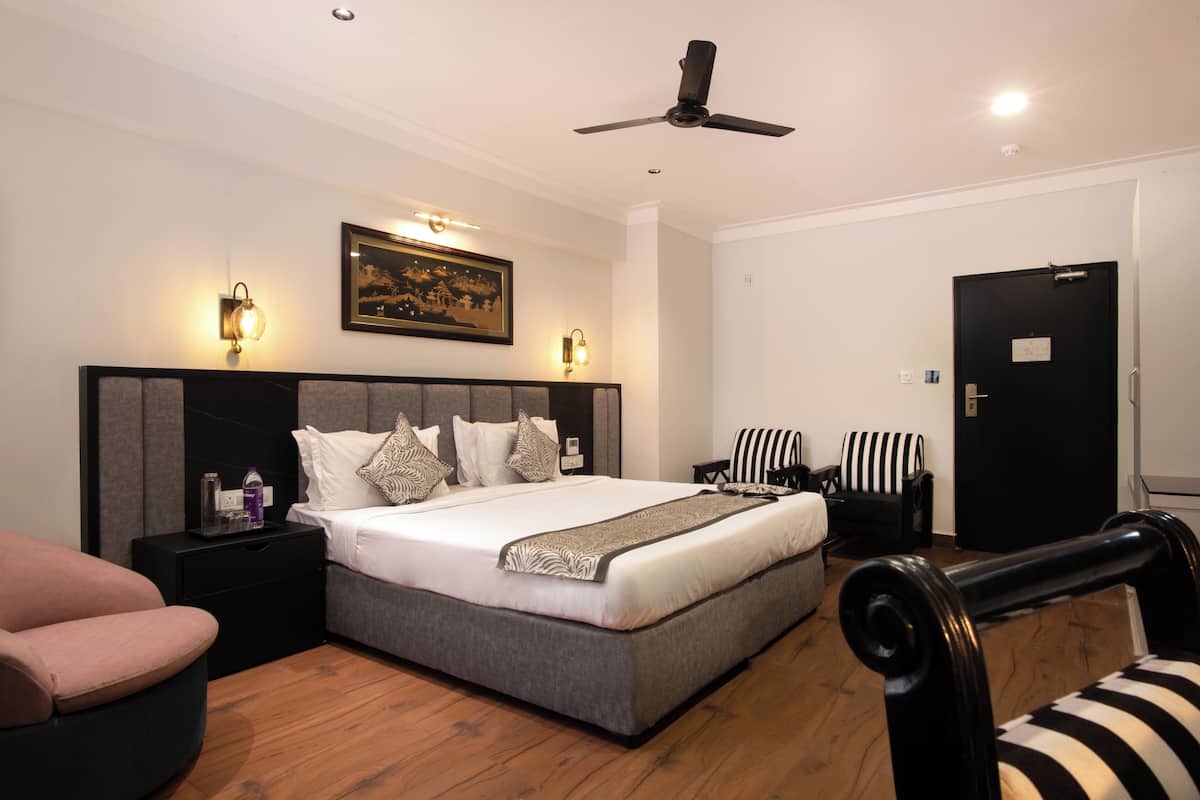 A bedroom with a large bed, bedside tables, a ceiling fan, and a door.