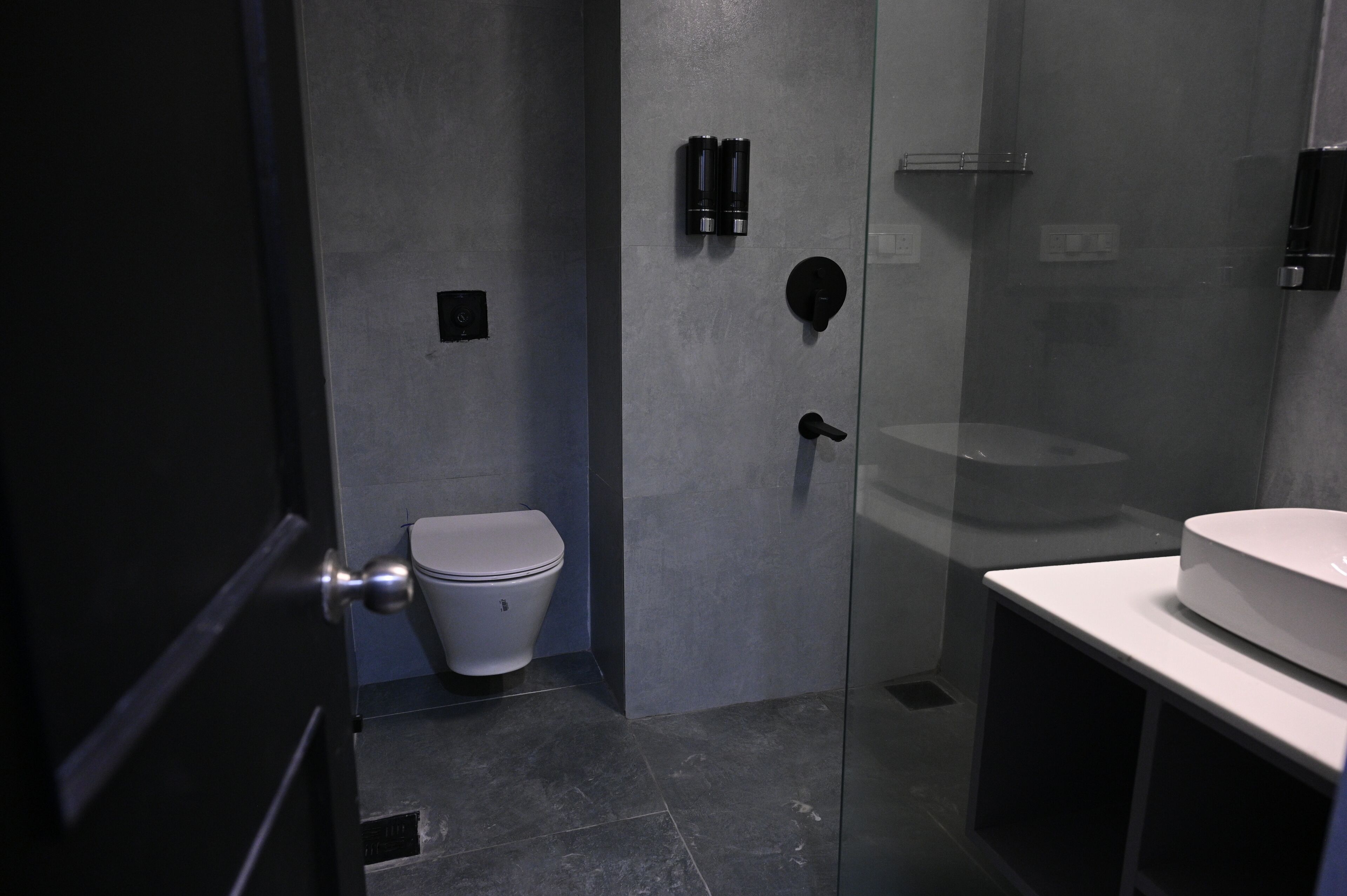 Een moderne badkamer met toilet, een douchecabine van glas en een wastafel.