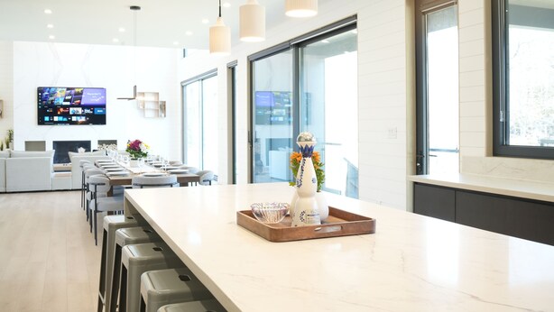 Une cuisine moderne avec un long comptoir, des tabourets de bar et un téléviseur fixé au mur.