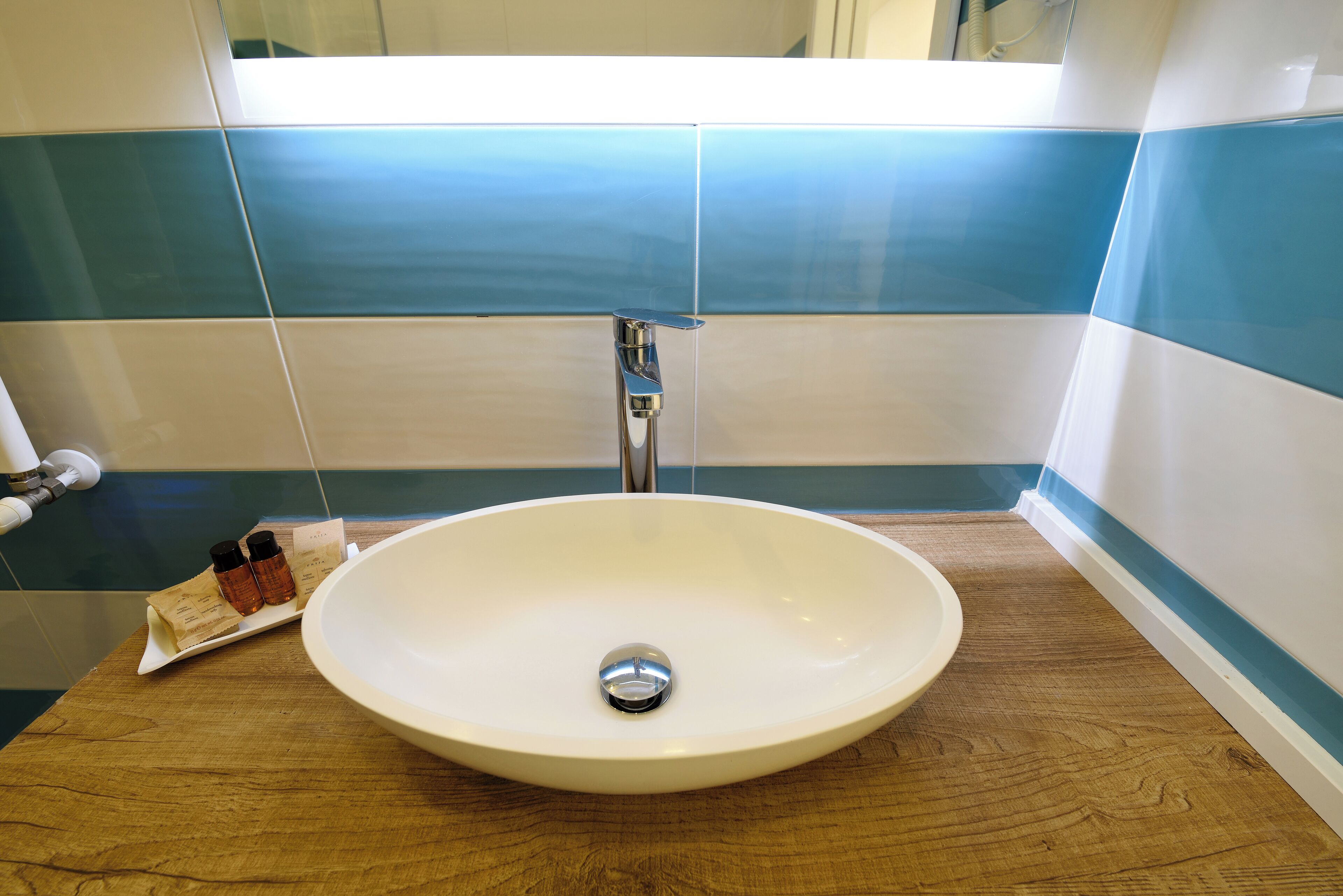 A bathroom with a white sink, a wooden countertop, and blue and white tiles on the walls.