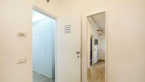 Een gang met een witte deur, een spiegel en een bord aan de muur.