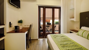 Hotelkamer met een bed, een bureau, een stoel, een televisie, een airconditioner en een balkon met een tafel en stoelen.