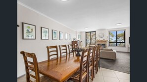 Enjoy meals in this dining area with a wooden table and six chairs, surrounded by artwork and a fireplace.