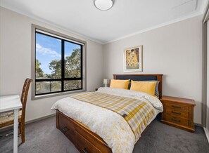 Relax in this cozy retreat with a large bed, nightstand, and desk, featuring a beautiful view of the surrounding landscape.