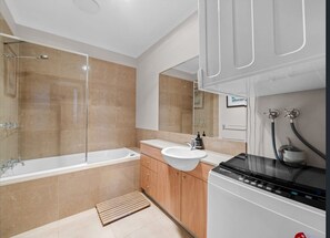 Features a bathtub, glass-enclosed shower, and sink with vanity.