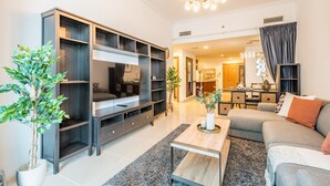 Un salon moderne comprenant un grand meuble de rangement pour appareils multimédias, un canapé, une table basse et une plante en pot.