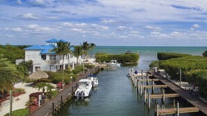 A marina with boats docked, a dockside building, and a clear view of the ocean. - Ocean Pointe Ocean View w/heated pool beach marina (Tavernier)