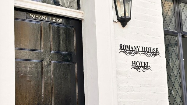 Une porte noire avec une enseigne indiquant « HÔTEL ROMANY HOUSE ».