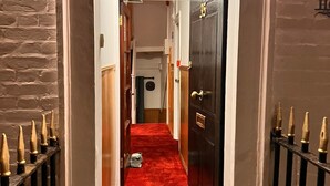 L’entrée d’un hôtel, avec un tapis rouge, une porte en bois et une enseigne indiquant « ROMAN HOUSE ».