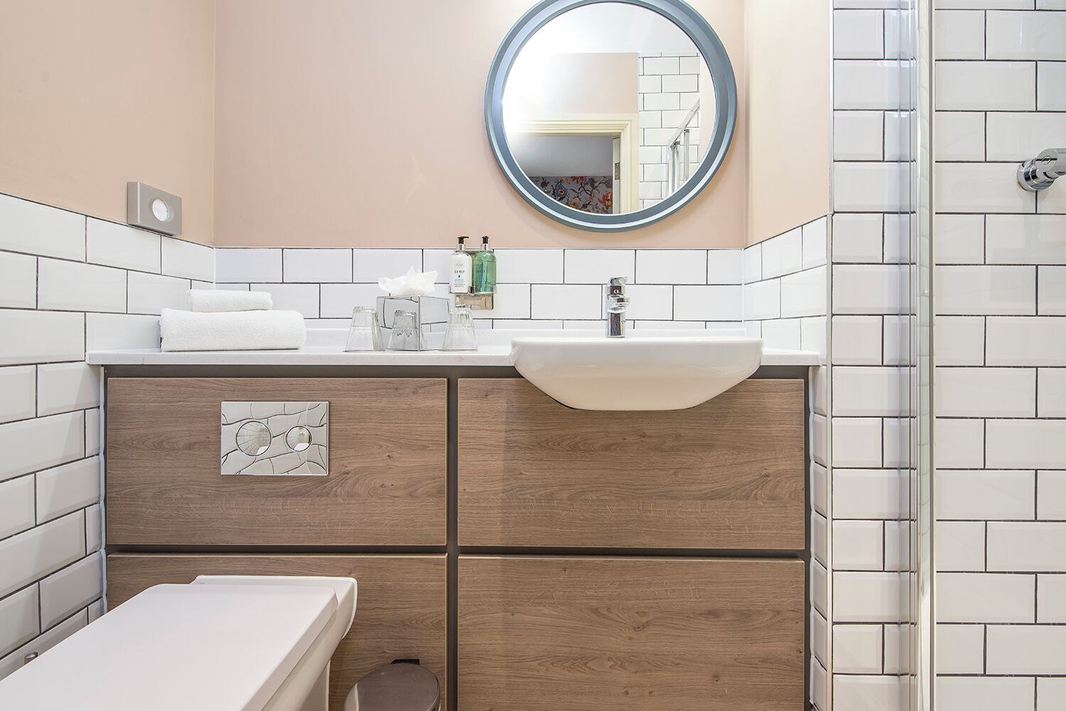 A bathroom with a white sink, wooden vanity, and a mirror.