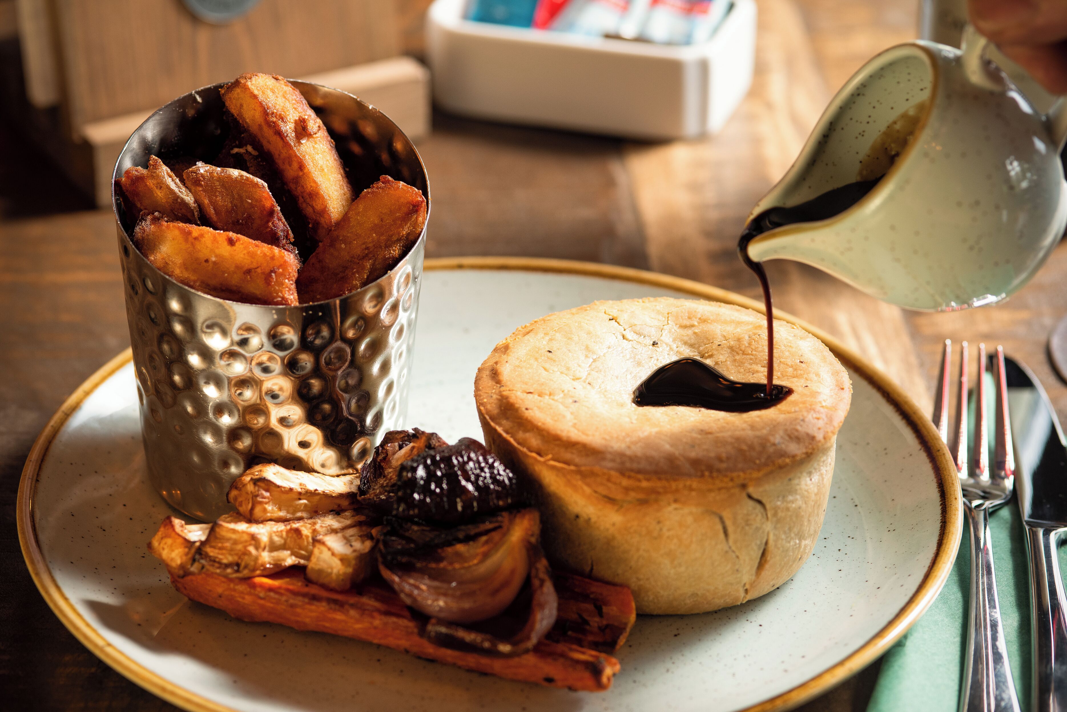 Une assiette avec une pâtisserie cuite au four, un récipient en métal contenant des pommes de terre frites et un petit bol de sauce.