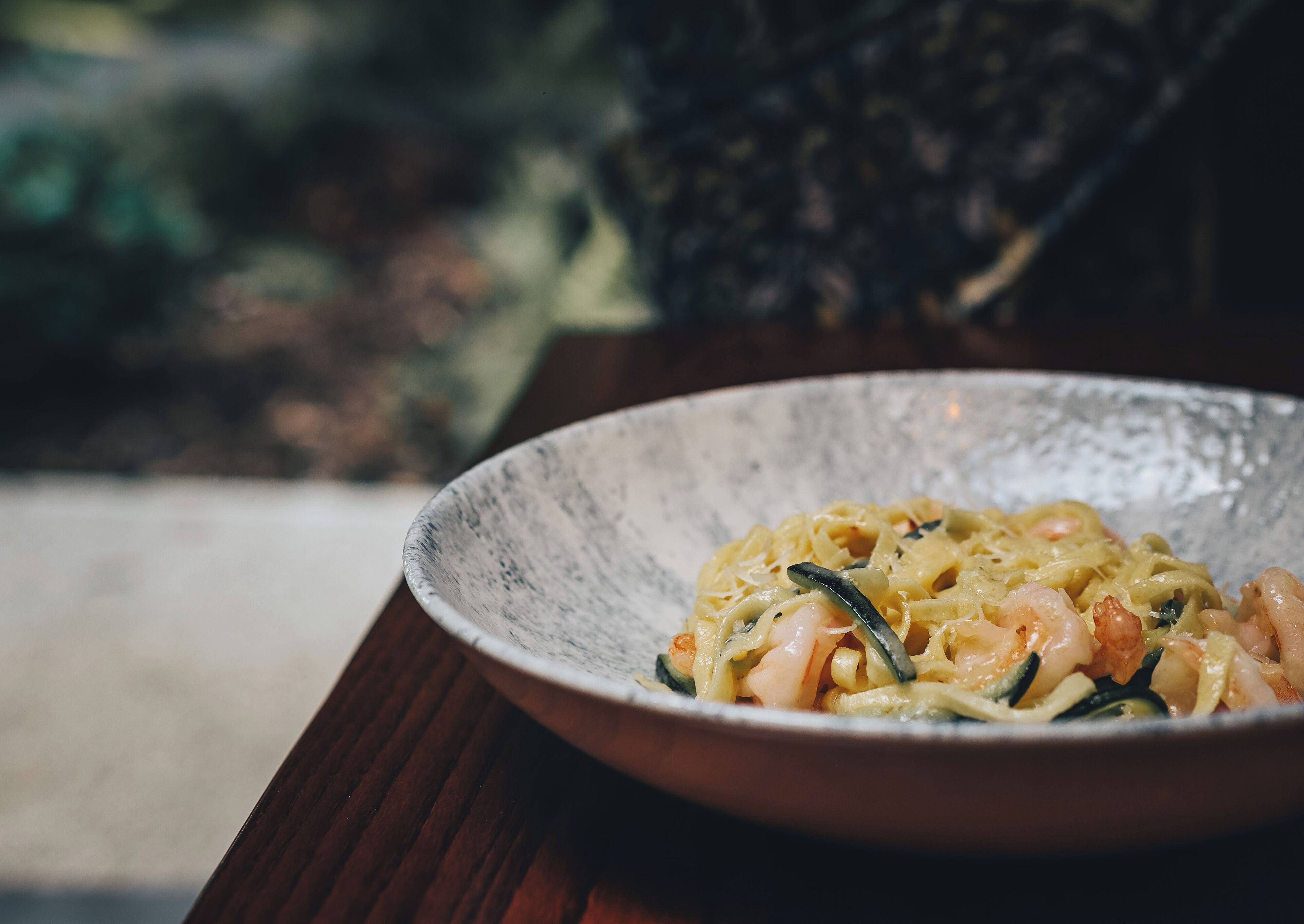 Un bol de pâtes aux crevettes, posé sur une table en bois.