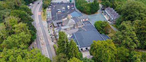 Et luftfoto viser en bygning med parkeringsplads, omgivet af frodig vegetation.