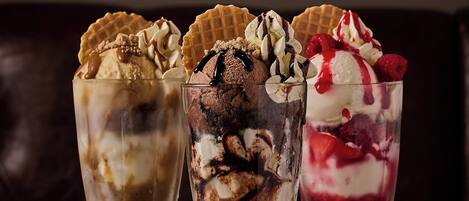 Three dessert glasses on a wooden table with a framed picture in the background.