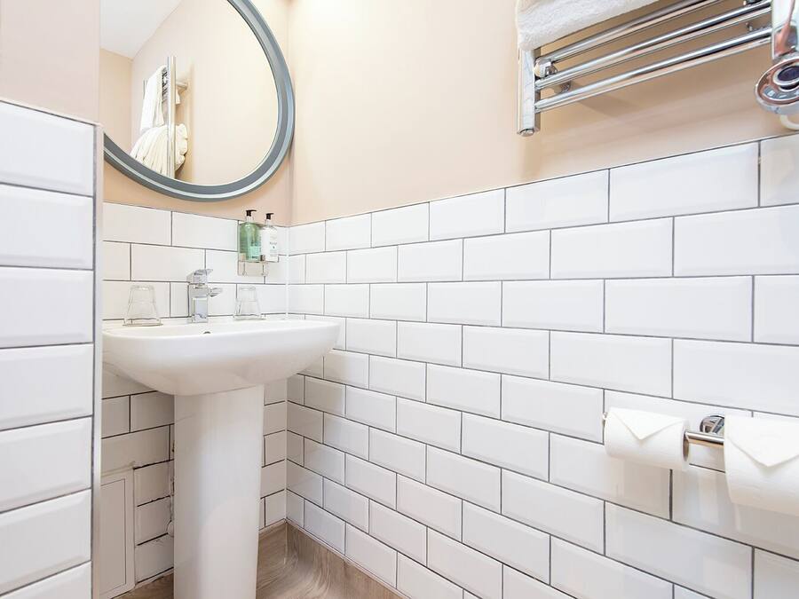 A bathroom with white tiles, a sink, a mirror, and a towel rack.