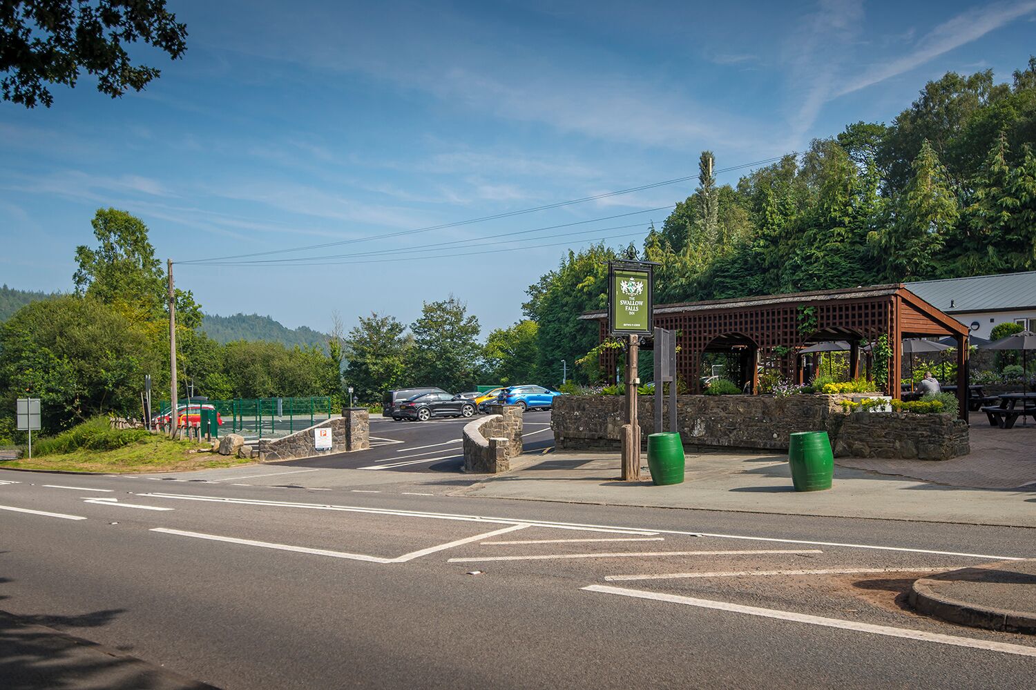 A road intersection with a pedestrian crossing, a parking area, and a gazebo with outdoor seating.