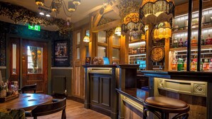 A bar area with wooden furniture, a reception desk, and a bar counter with bottles.