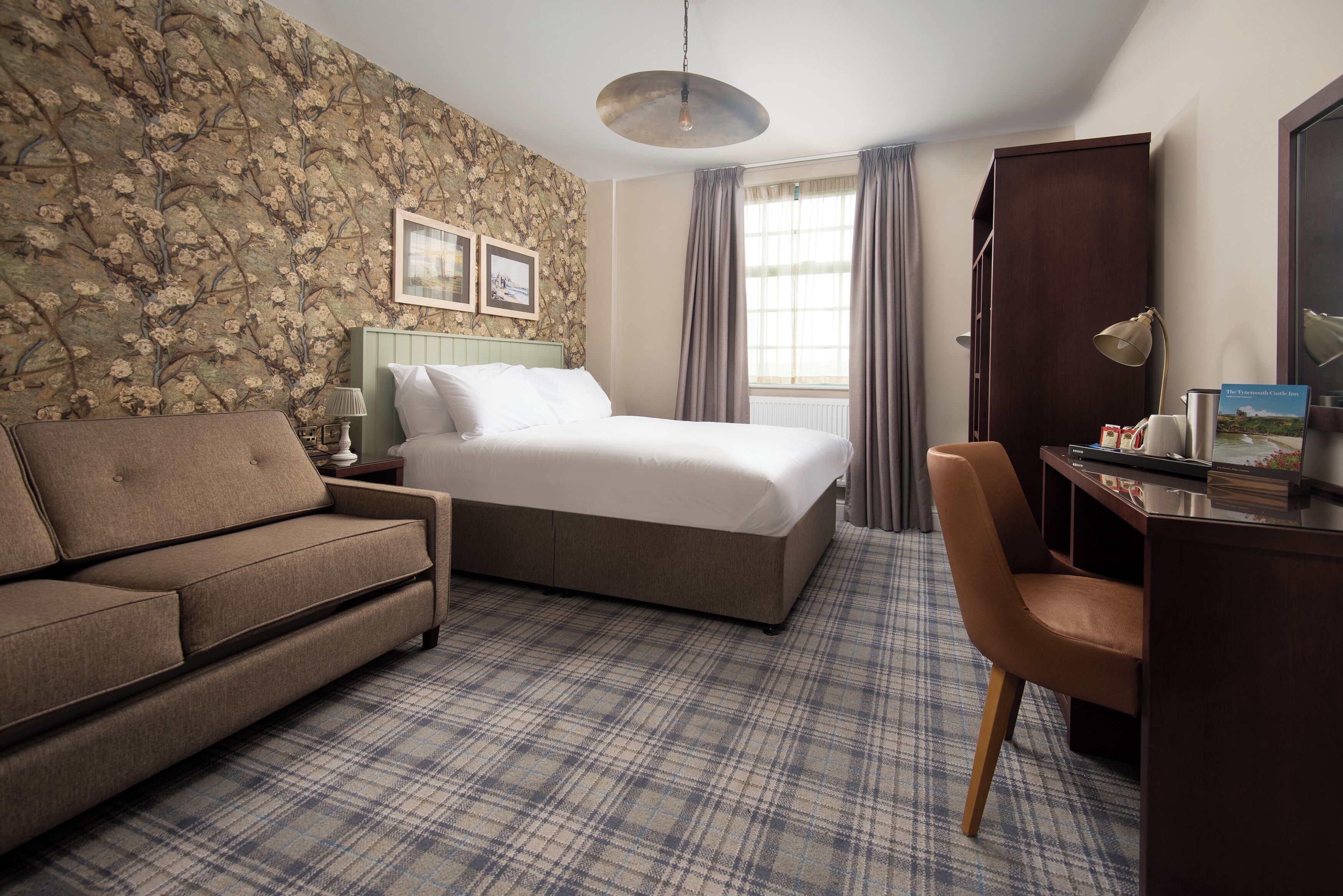 A hotel room with a bed, a sofa, a desk, and a chair.
