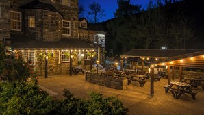 A stone building with outdoor seating and string lights.