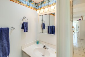 Een badkamer met een wit wastafel, een spiegel en twee handdoeken die aan handdoekhouders hangen.