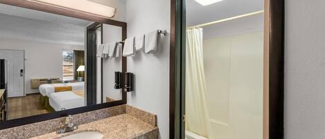 Un baño moderno con un lavabo de granito, un espejo grande, un inodoro y una ducha con cortina.