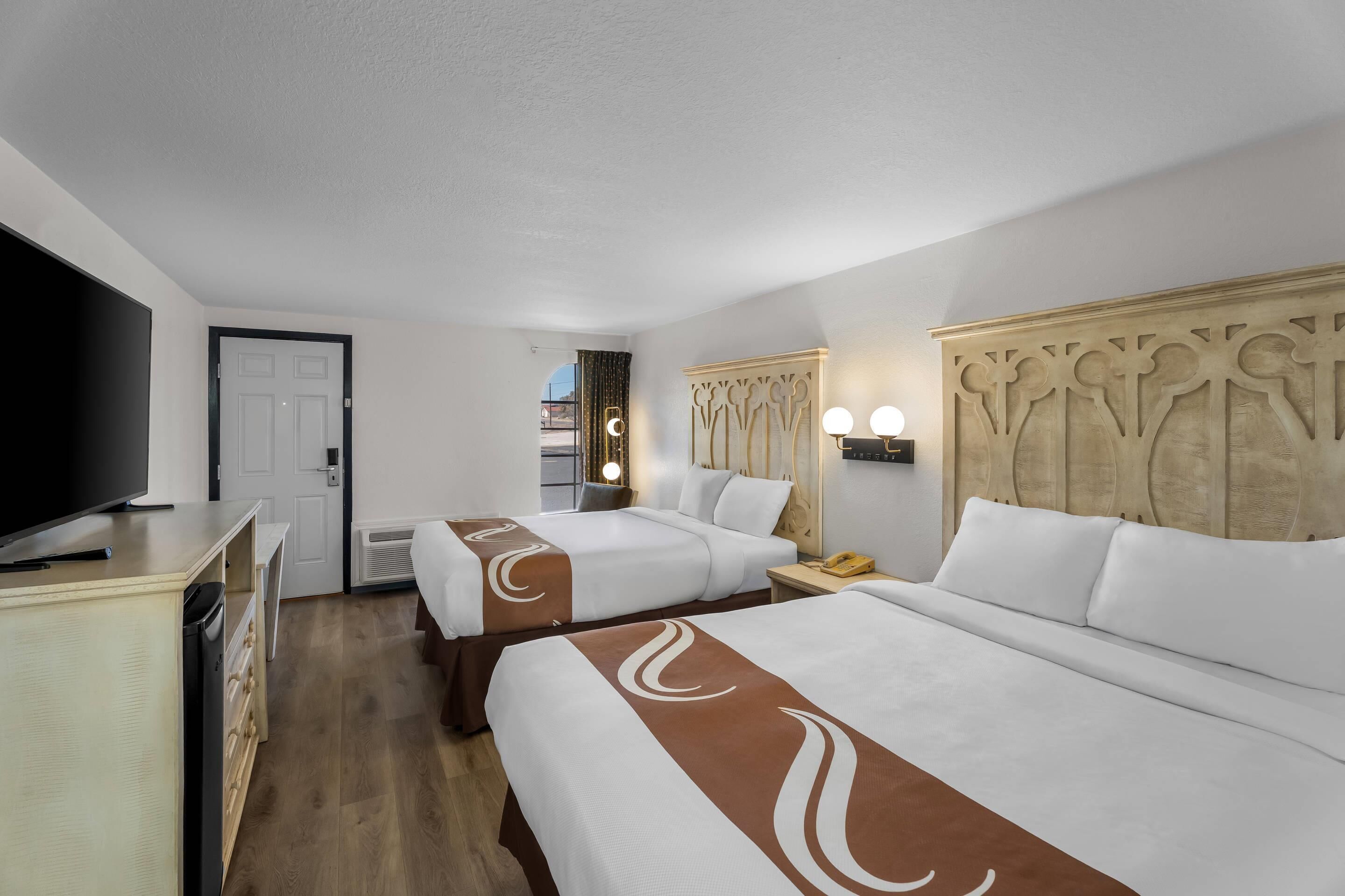 A hotel room with two beds, a television, a desk, and a wardrobe.