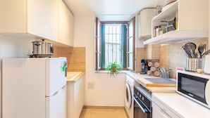 Una cocina compacta equipada con refrigerador, microondas, horno y lavamanos.