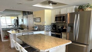 Una cocina moderna con una isla central, electrodomésticos de acero inoxidable y armarios blancos.
